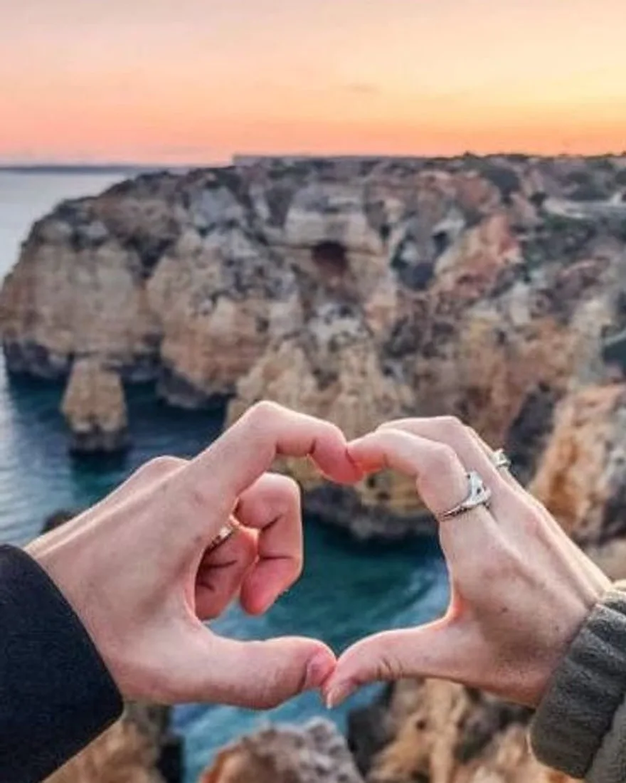 A couple's hands forming a heart in soft evening light