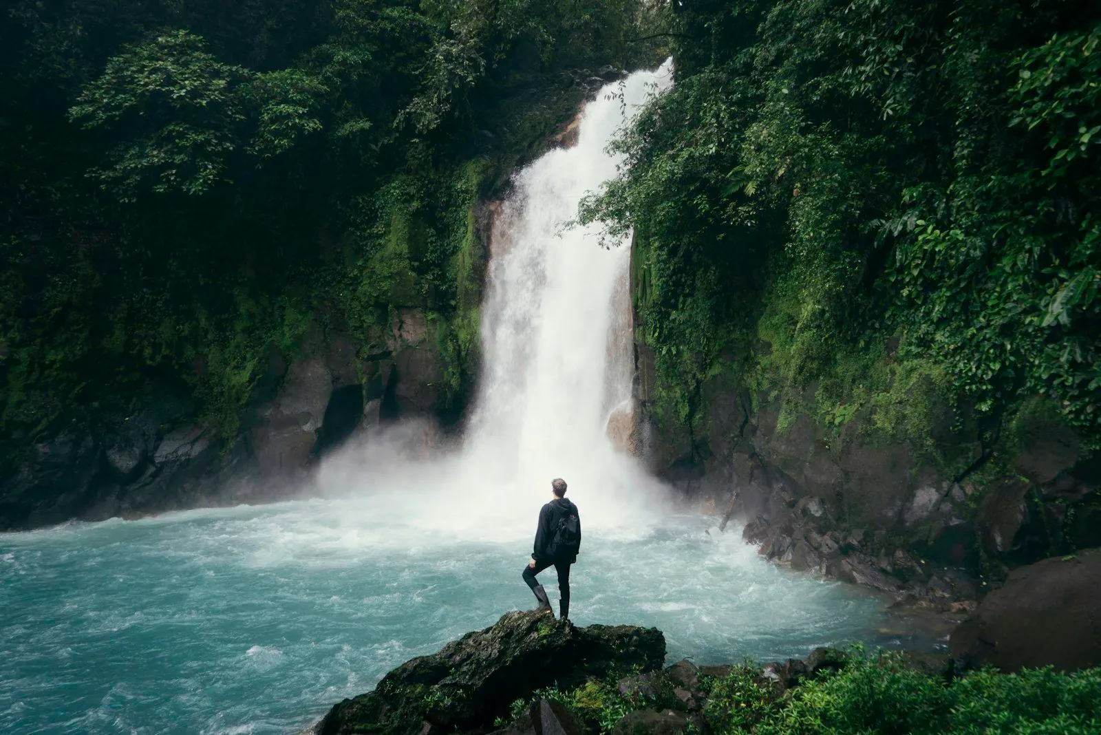A person standing before a waterfall